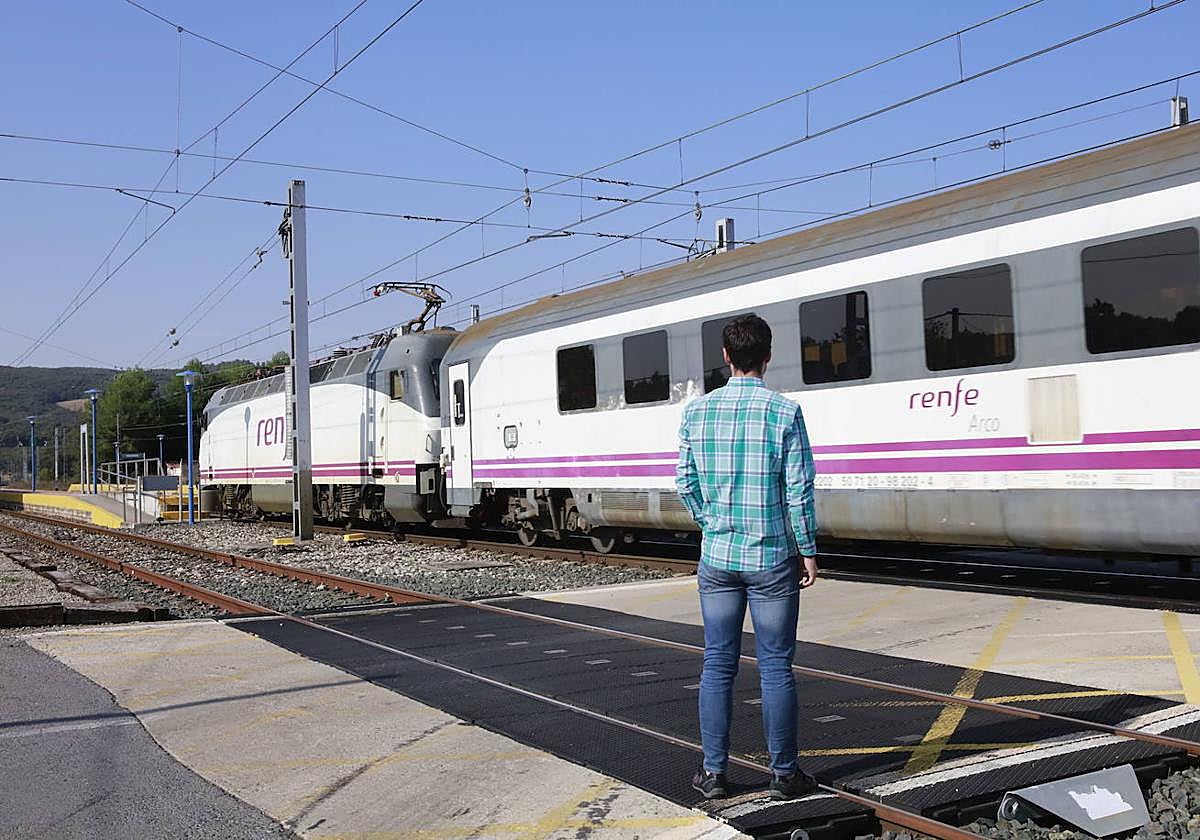 Un peatón espera a que pase el tren para cruzar el paso a nivel de Manzanos.