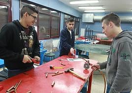 Tres estudiantes del módulo de Mantenimiento aprenden a soldar un tubo.
