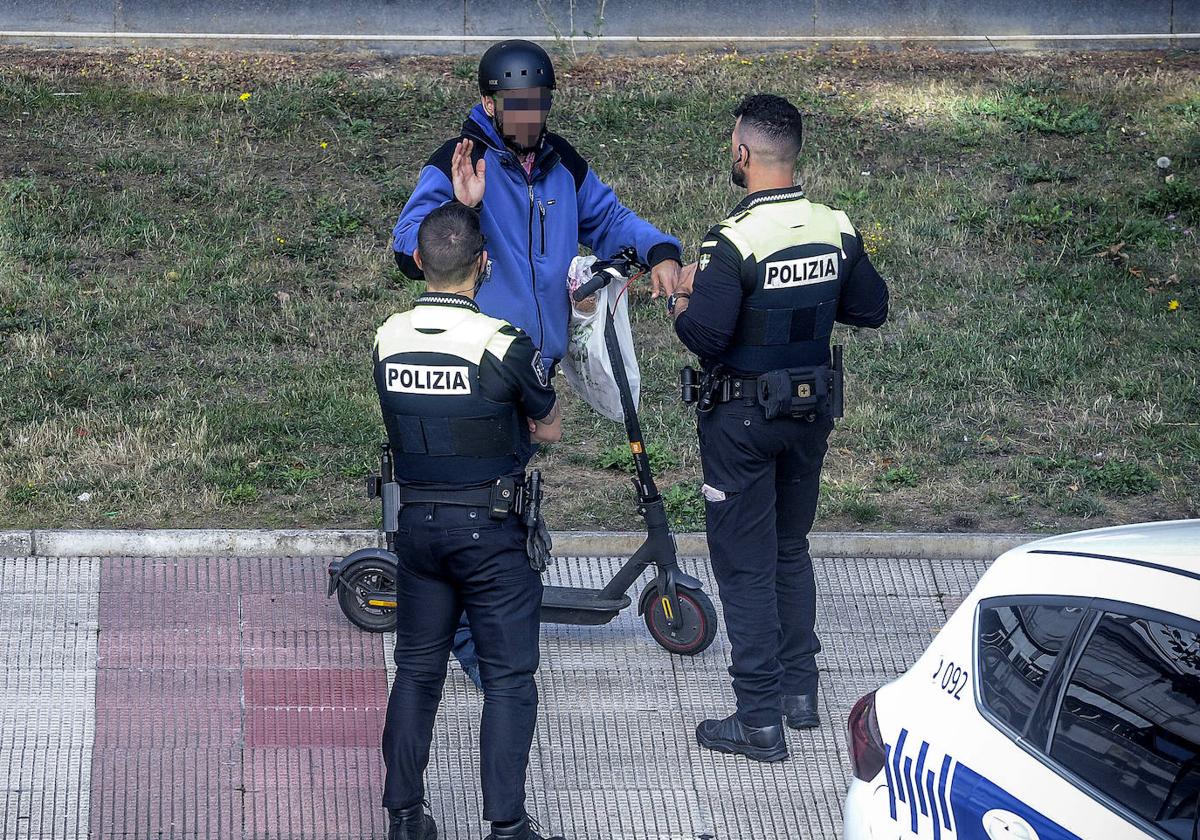 Dos agentes reprenden a un patinetero que va por la acera.