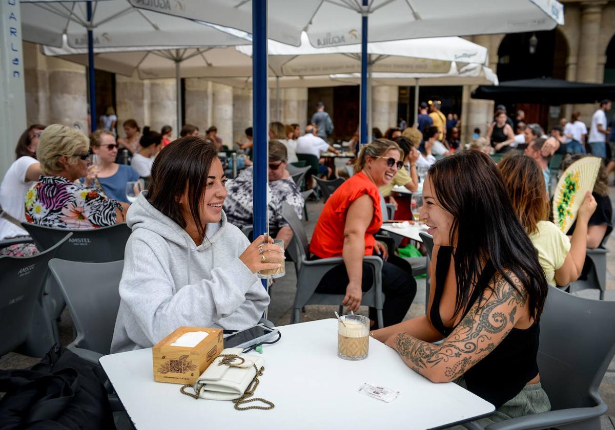 Dos jóvenes disfrutan de una terraza en la Plaza Nueva de Bilbao.