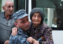 Un agente de policía armenio ayuda a una refugiada de la región de Nagorno Karabaj.