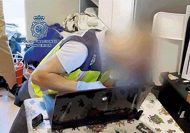 Los agentes inspeccionando un ordenador hallado en la vivienda.