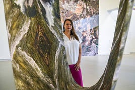 La artista colombiana afincada en California Carolina Caycedo, junto a su retrato de un río y la pieza 'Tierra de amigos', al fondo, que bautiza a la exposición en el Museo Artium.