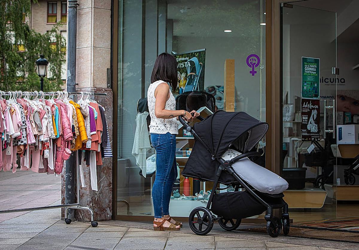 Una mujer mira ropa de niño en un comercio de Gernika.
