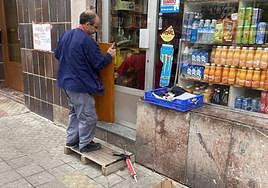 Un operario ultima el arreglo de la puerta fracturada por los asaltantes.
