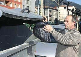 Un hombre tira una bolsa de basura en un contenedor en Llodio.