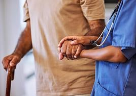 Una terapeuta ayuda a caminar a un paciente con alzhéimer