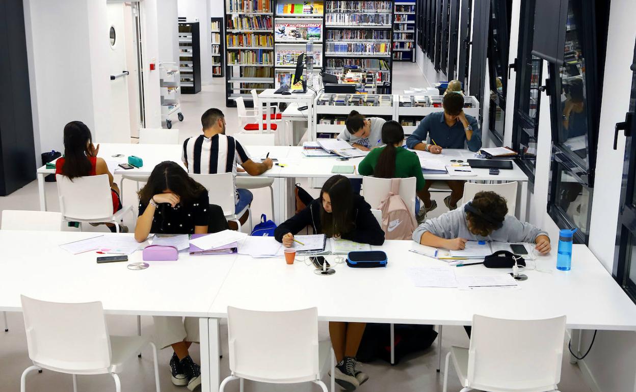 Varios estudiantes preparando exámenes en una biblioteca. 