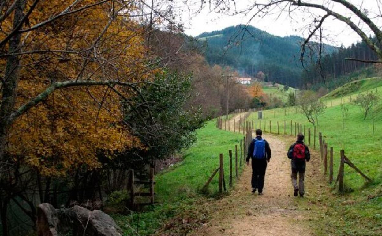 Dos senderistas caminan por parte del trazado por el río Lea que transcurre por Lekeitio. 