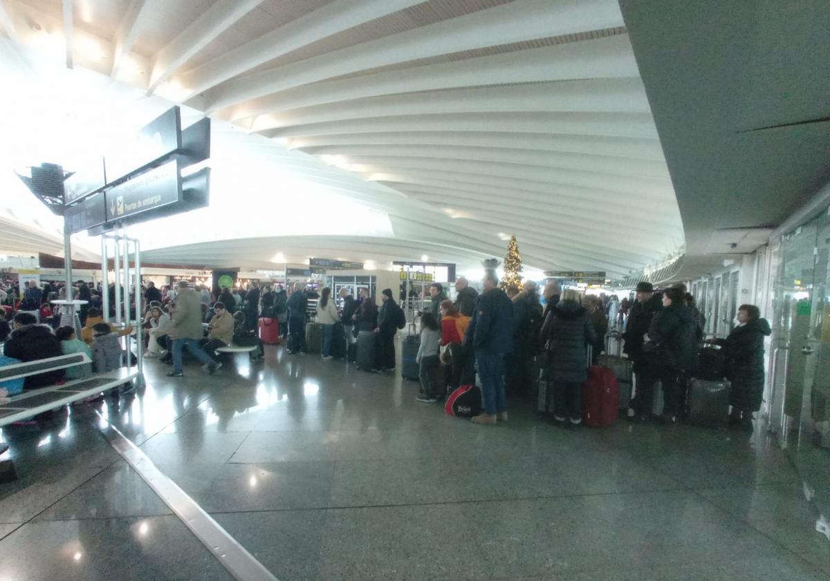 Imagen principal - Estampas de este viernes en el aeropuerto de Loiu, donde se han formado larguísimas colas a lo largo de la mañana que prácticamente salen por la puerta de acceso a la terminal. Las maletas se amontonan en la zona de recogida