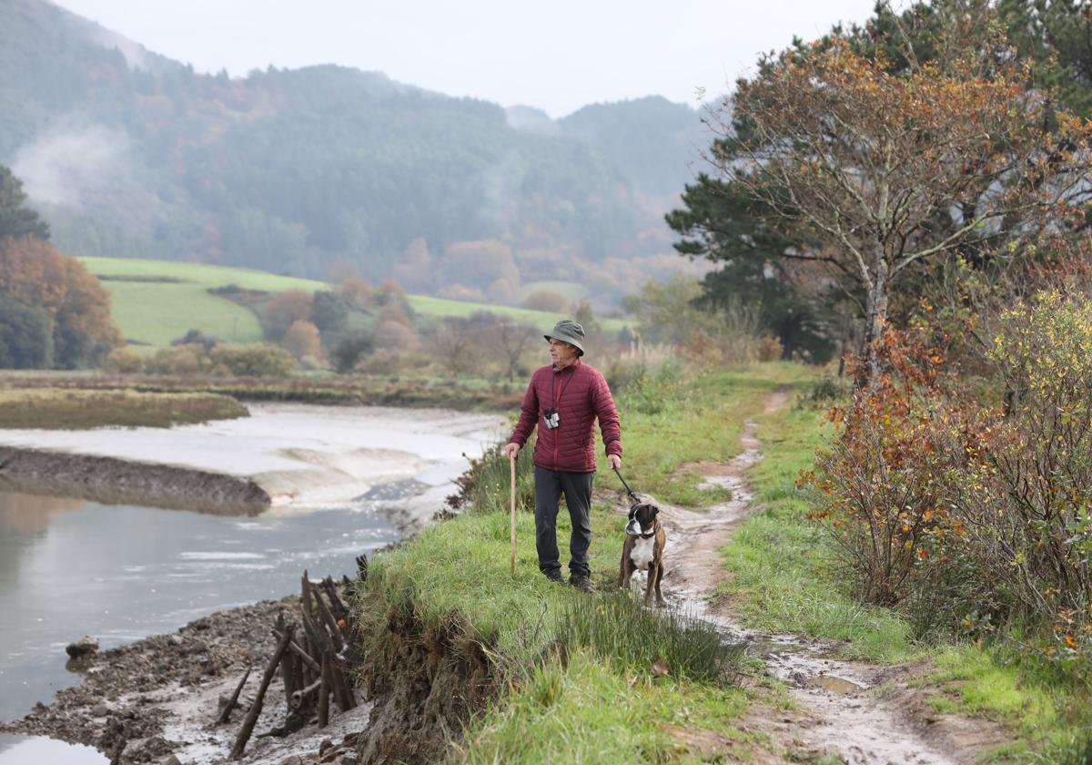 Un senderista pasea junto a su perro por una ruta de Urdaibai.