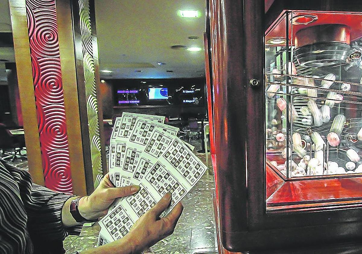 Una persona sostiene cartones de bingo en un salón de juegos.