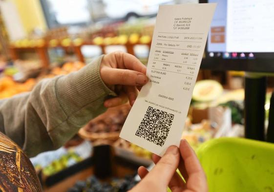 Una comerciante alavesa sujeta un tícket con código QR.