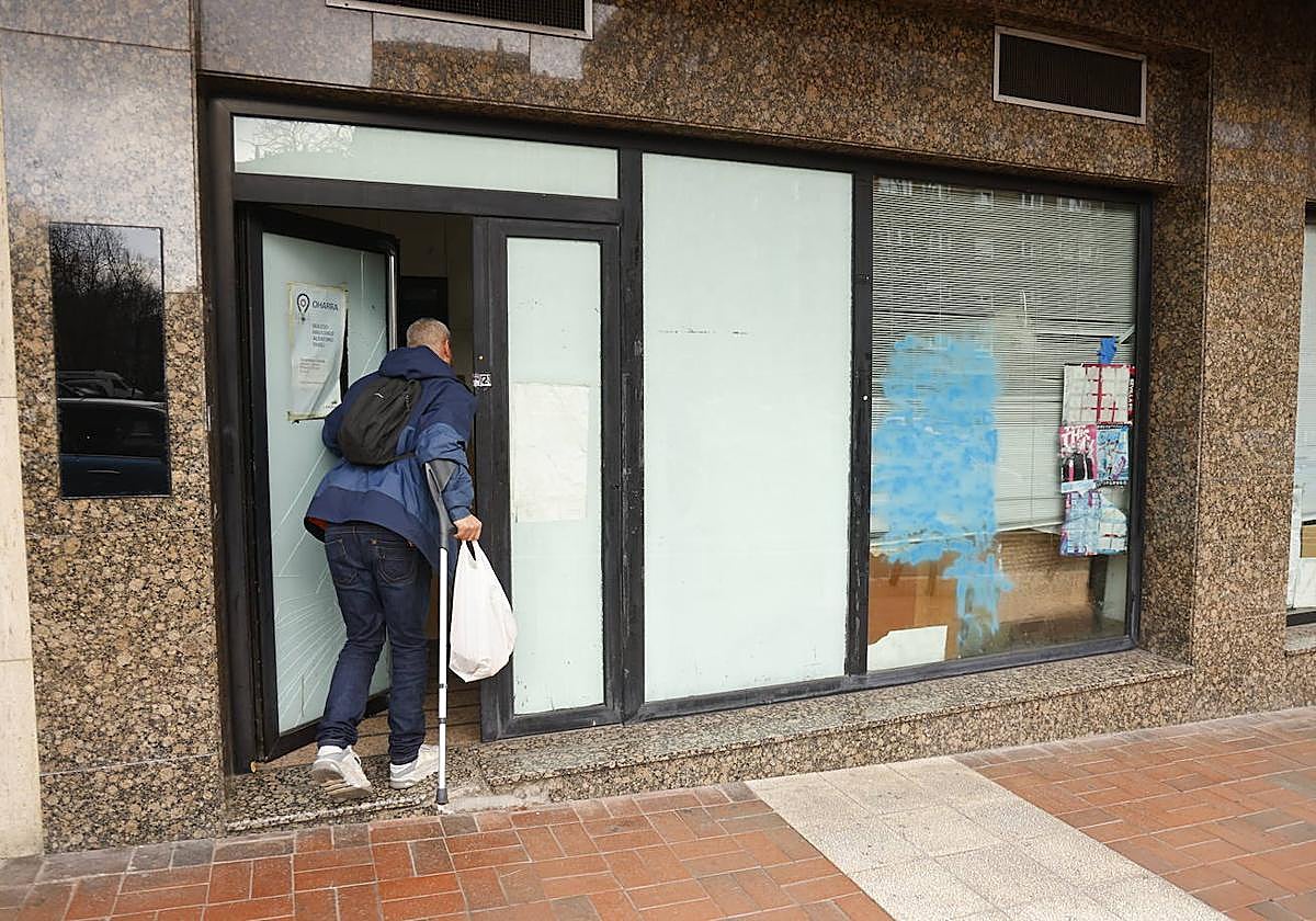 Un okupa, ajeno a esta noticia, entra en la lonja okupada donde la Policía Local encontró los enseres robados.