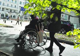 Un cuidador pasea a una persona dependiente en Bilbao.