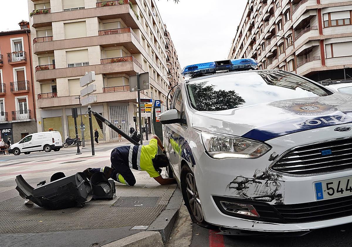 Un operario municipal inspecciona un coche patrulla involucrado en un accidente.
