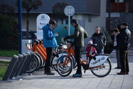 Dos usuarios toman una de las bicicletas del servicio público.