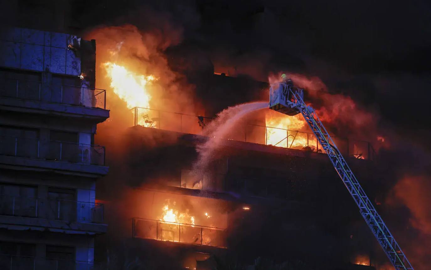 Un bombero echa agua pulverizada sobre la fachada del edificio.