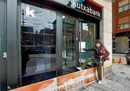 Una vecina de Erandio intenta acceder a la sucursal de Kutxabank que ayer sufría aún los daños de la inundación del lunes.