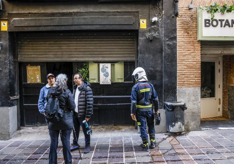 El dueño del local charla mientras los bomberos inspeccionan el bar