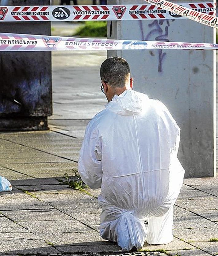 Imagen secundaria 2 - Un agente uniformado acompaña a una familiar del pequeño de 11 meses, mientras que otro graba desde la ventana donde ocurrieron los hechos. Un policía fotografía el lugar del impacto junto al pañal del bebé.