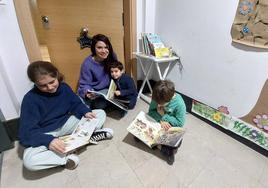 Lier junto a su madre, Itziar Llarena, y sus vecinos Carla y Mateo, leyendo varios de los libros de la biblioteca compartida que han creado en su edificio.