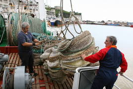 Dos arrantzales manipulan una red en un pesquero del puerto de Ondarroa.