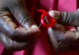 Una mujer prepara en Kenya un lazo rojo de solidaridad con los pacientes afectados por el virus del sida.