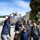 Un grupo de turistas se fotografía junto al Guggenheim