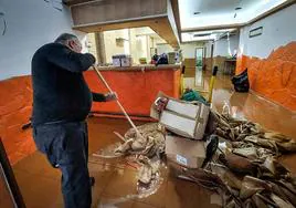 Un vecino recoge los objetos dañados por la pasada inundación en Erandio.