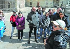 Turistas atienden a las explicaciones de una guía frente al pórtico de la iglesia vitoriana de San Miguel.