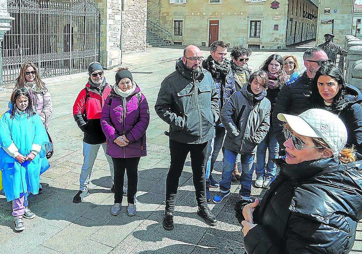 Turistas atienden a las explicaciones de una guía frente al pórtico de la iglesia vitoriana de San Miguel.