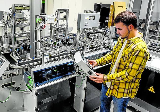 Adrián manipula la Fábrica inteligente en un laboratorio de Deusto.