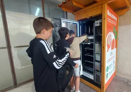 Alumnos de la ikastola Eleizalde de Bermeo surten la máquina 'vending' gratuita con los tupper envasados con el excedente de su comedor escolar.