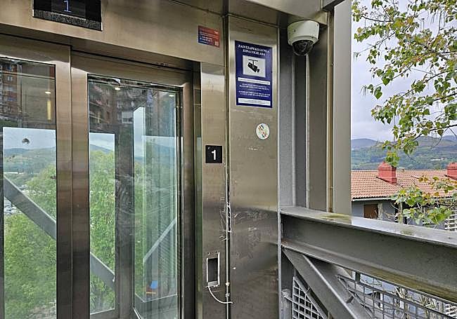 El botón de llamada arrancado con los cables al aire bajo una de las cámaras que hay en los ascensores.