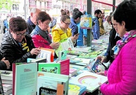 Varias lectoras hojean los libros de uno de los puestos, en una de las ediciones anteriores del Día.