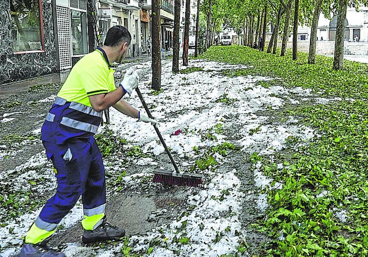 Un trabajador retira granizo y hojas de la plaza de los Fueros.