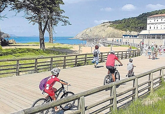 Una familia pasea en bicicleta por la playa de Gorliz.