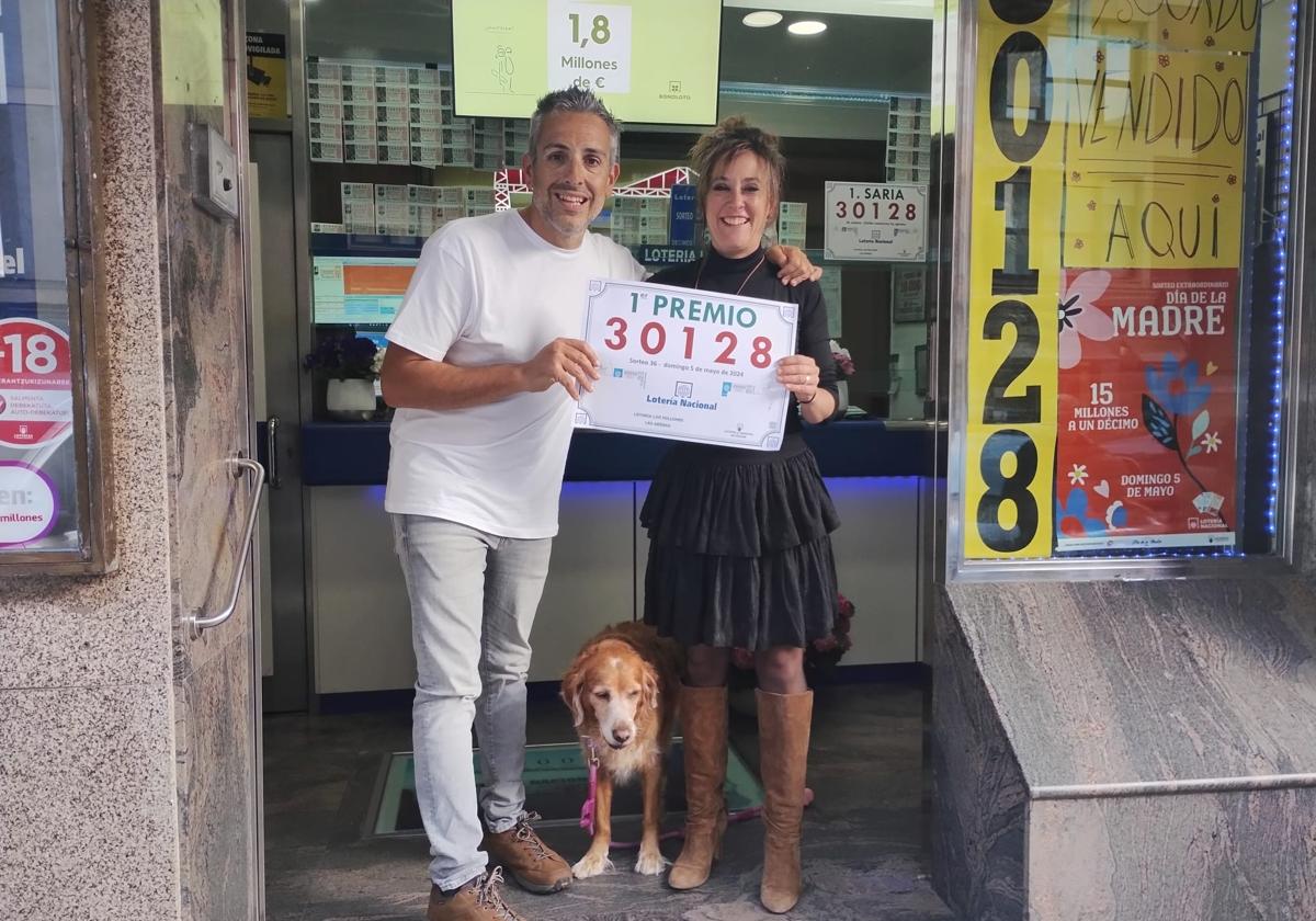 Jon Idirin y Nora Calzada, propietarios de la administración de lotería 'Los Millones' con el cartel del Gordo del Sorteo Extraordinario del Día de la Madre.