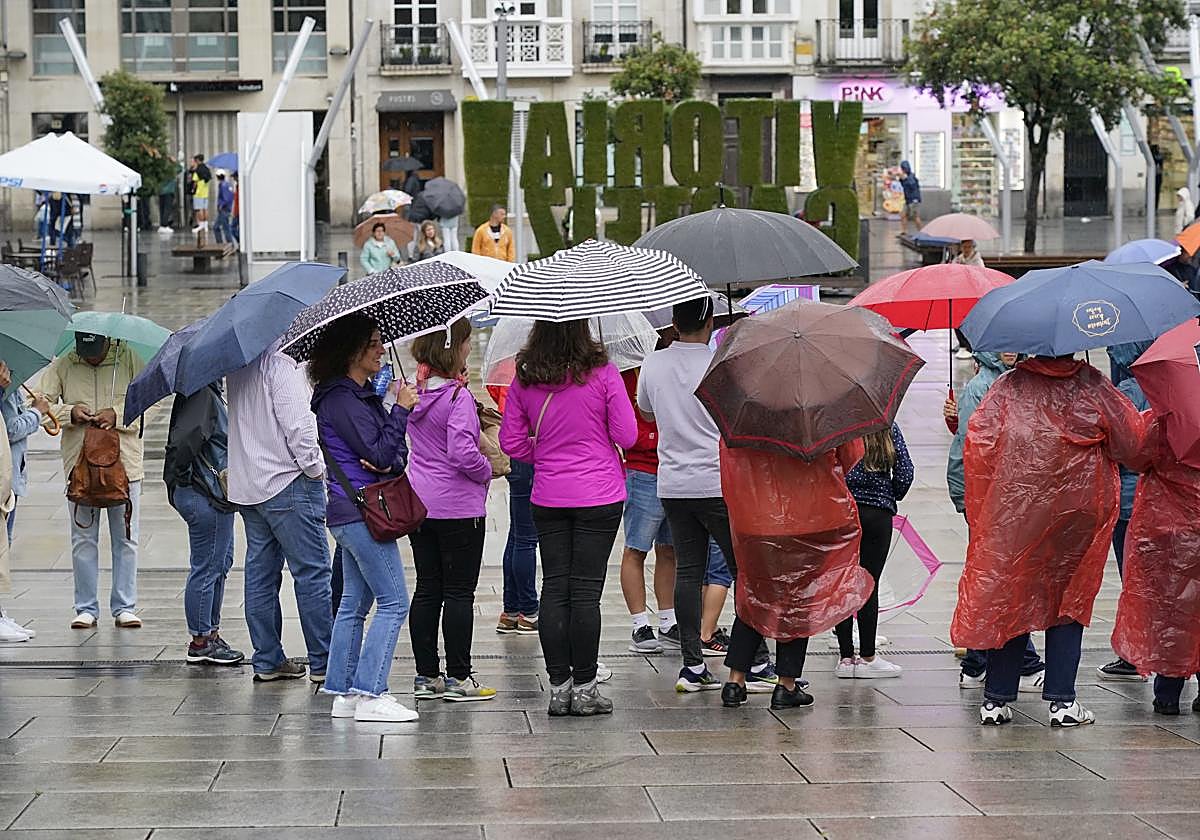 Varias personas se protegen de la lluvia en la plaza de la Virgen Blanca.