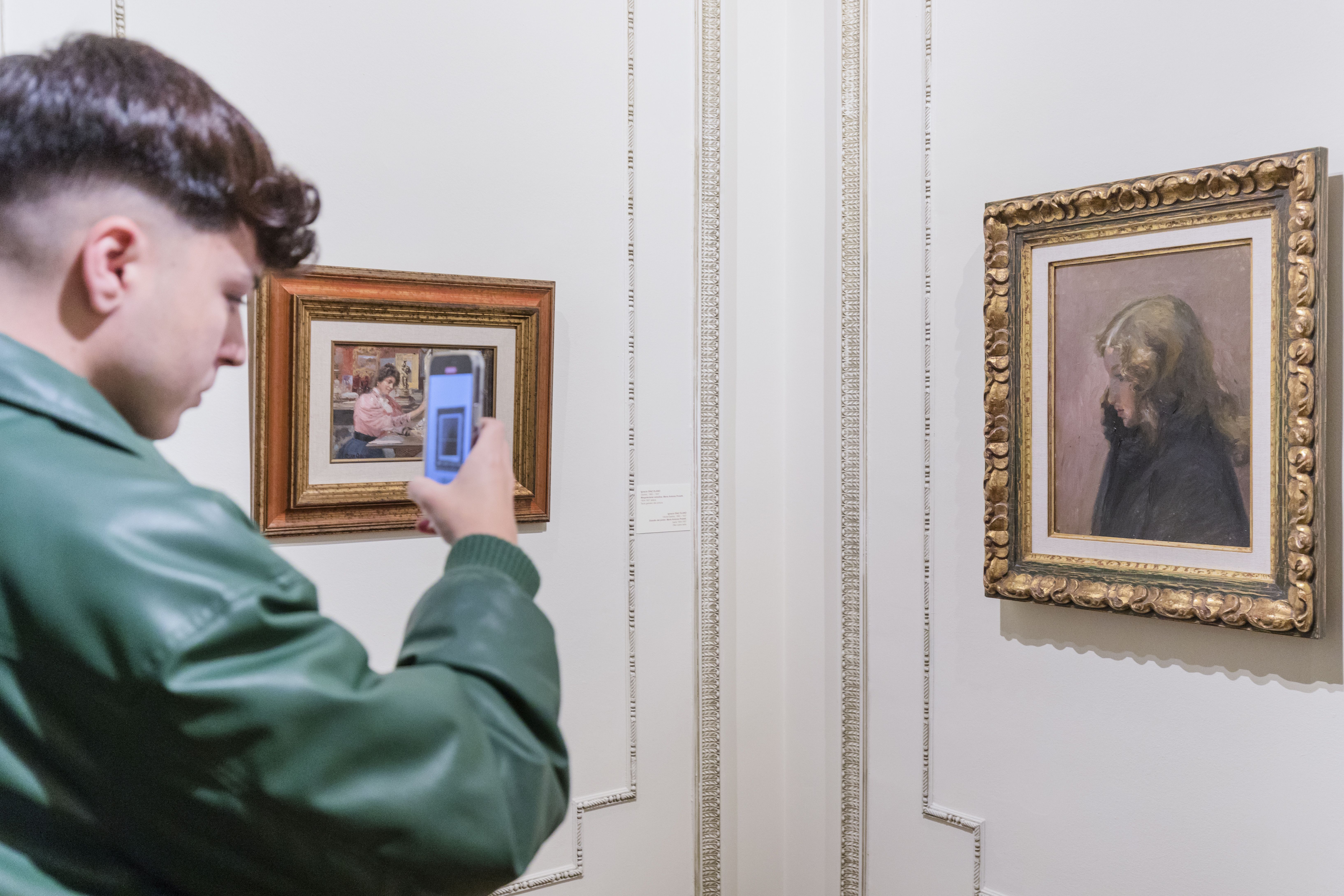 Un espectador fotografía con su un cuadro de la muestra 'María Antonia Proietti, la modelo italiana'. En él se muestra a la hija de la modelo.