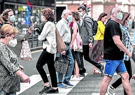 Un grupo de personas, la mayoría de elos con mascarilla, cruzando un paso de cebra en Bilbao.