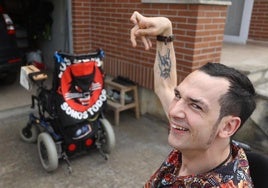 Héctor, en su casa de Guriezo, junto a su silla eléctrica, adornada con el emblema del grupo gallego Los Suaves.