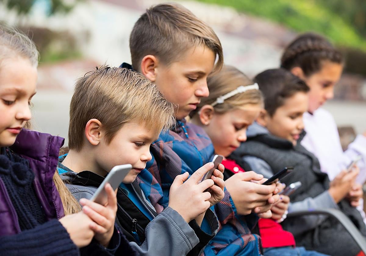 Niños de diferentes edades usando el móvil.