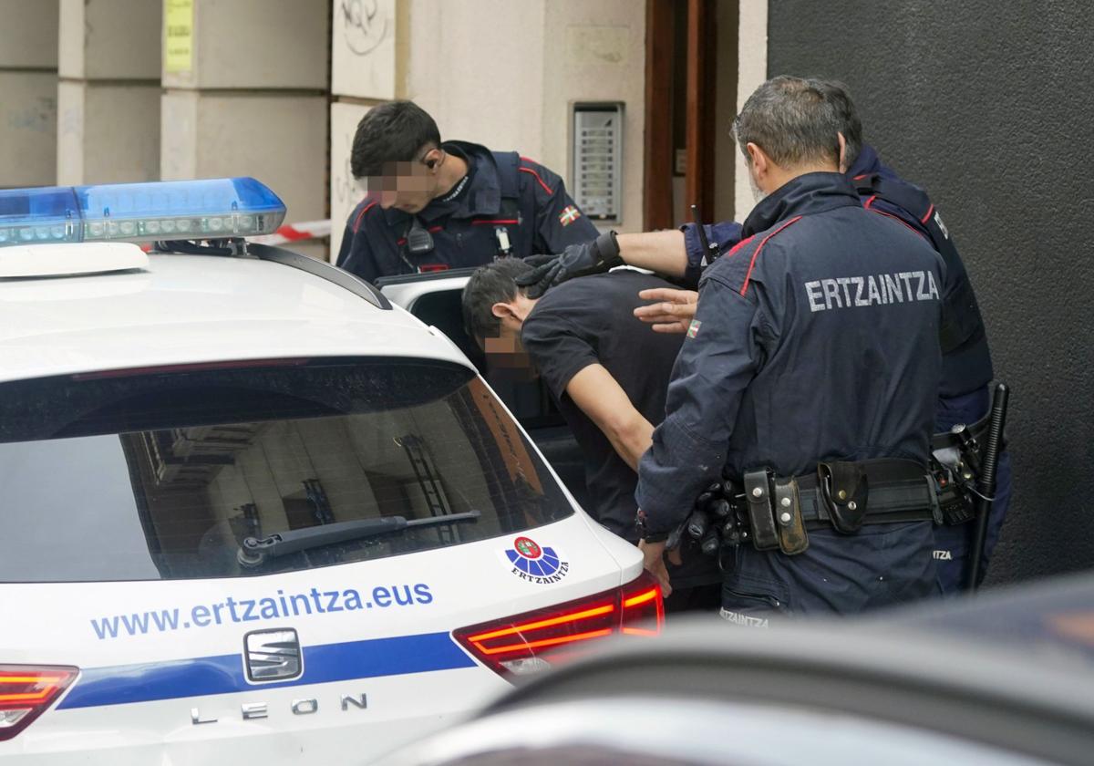 Ertzainas introducen en un coche patrulla a uno de los dos detenidos.