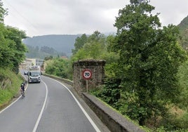 Tramo de la carretera en la que a la derecha se percibe parte del muro junto a los pilares del antiguo puente ferroviario que se usará como bidegorri.