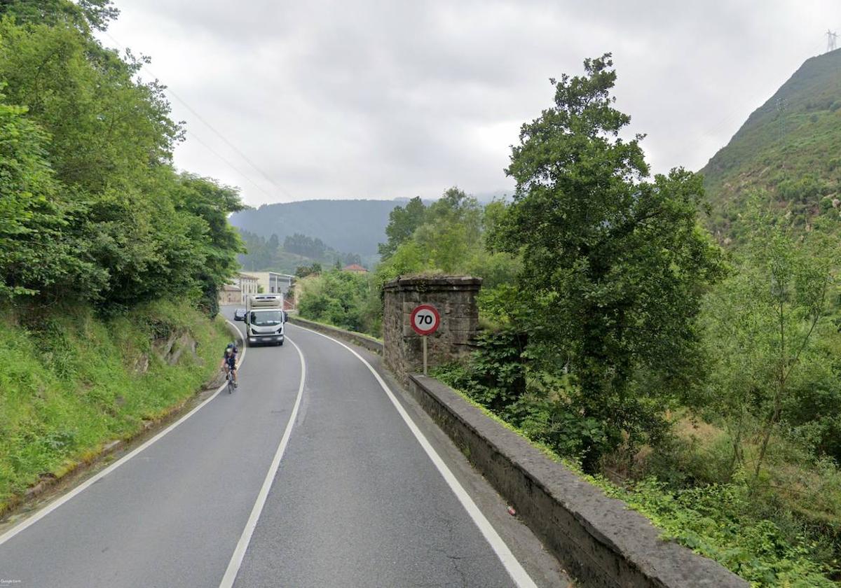 Tramo de la carretera en la que a la derecha se percibe parte del muro junto a los pilares del antiguo puente ferroviario que se usará como bidegorri.