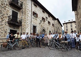 Arriba, numerosos participantes posan en las calles de Artziniega con sus bicis antiguas y trajes de época.
