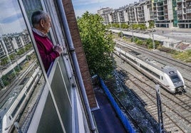 Un hombre observa desde su ventana un tren que abandona la estación de la calle Dato.