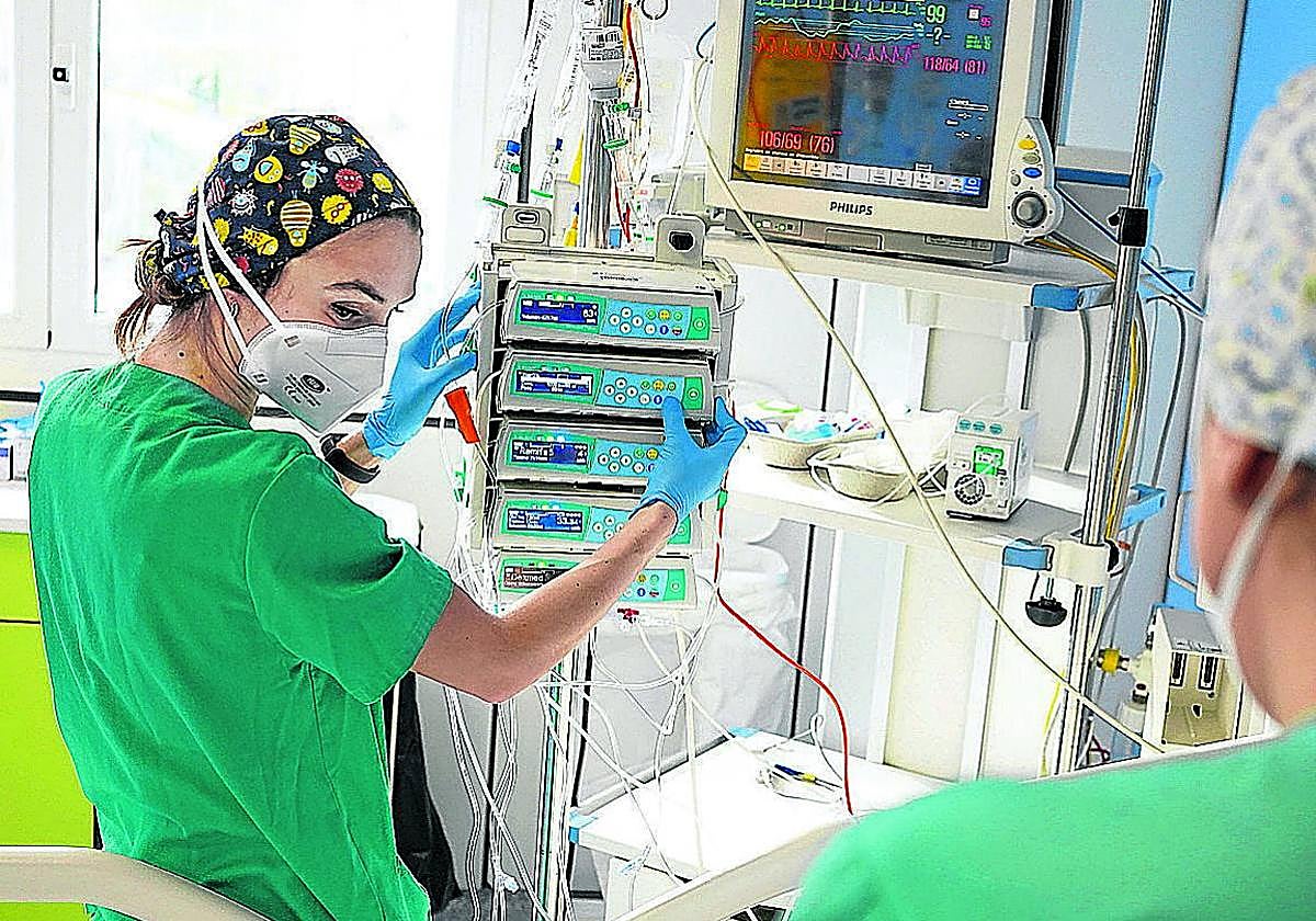 Dos sanitarias de Osakidetza junto a la cama de un centro hospitalario.